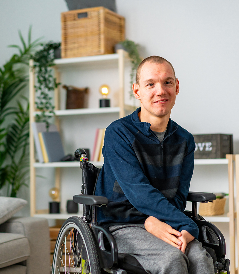 A man in a wheelchair smiles at the camera